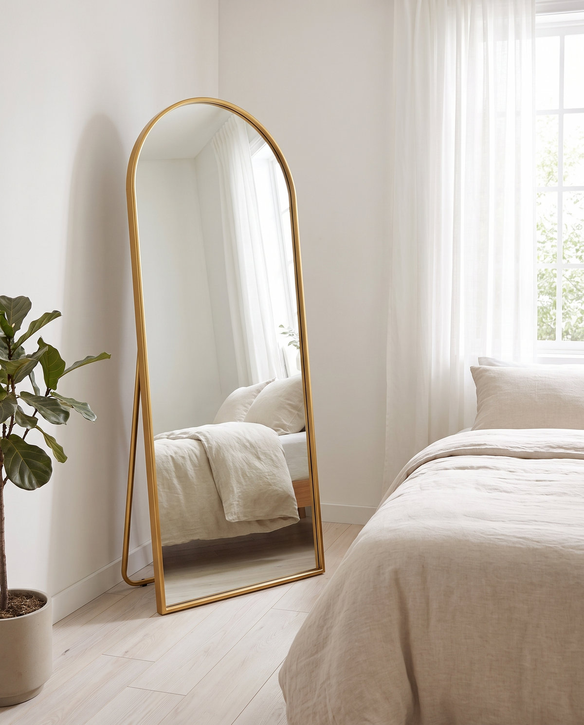 Arched Metal Full-Length Mirror, Gold finish, standing in bright bedroom